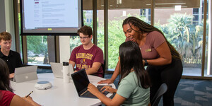 People gathering around a table talking with a power point presentation on a screen in the background