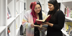 Two people standing in the middle of book stacks