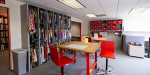 Room with draped fabric samples, mounted sample bins along the back wall, and a hightop table in the center.