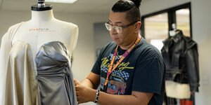 Student draping a garment with silver and cream fabric on a mannequin.