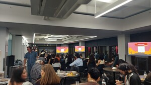 Photo of crowd at 2024 Indigenous Open Mic Poetry Night. Eli Shepherd (Diné) is playing his white Fender electric guitar on stage.