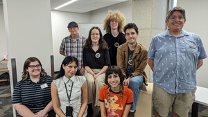 A group of people sitting and standing smiling for the camera