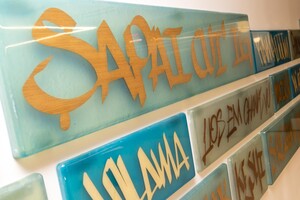 Detail of a glass art piece that says "Welcome" in many different Indigenous languages.