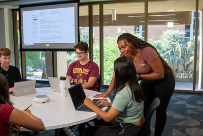 People gathering around a table talking with a power point presentation on a screen in the background